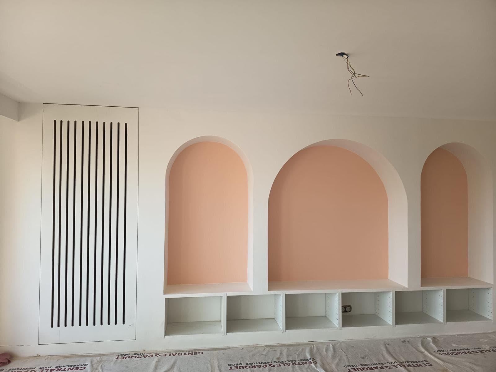 Niches en arche peintes en rose avec rangements bas et cache-radiateur à lames
