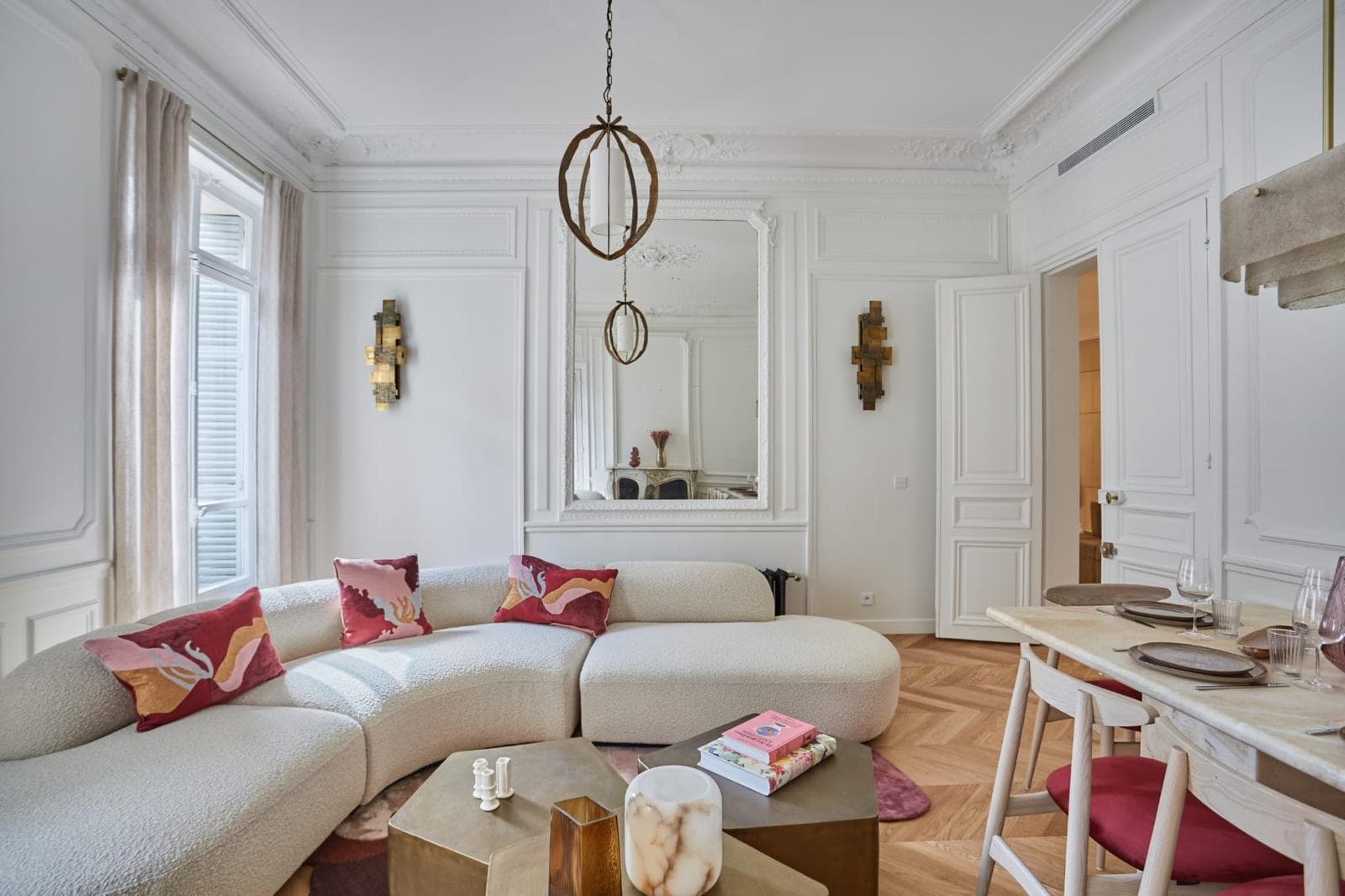 Salon haussmannien aux moulures restaurées, canapé courbe et miroir de cheminée