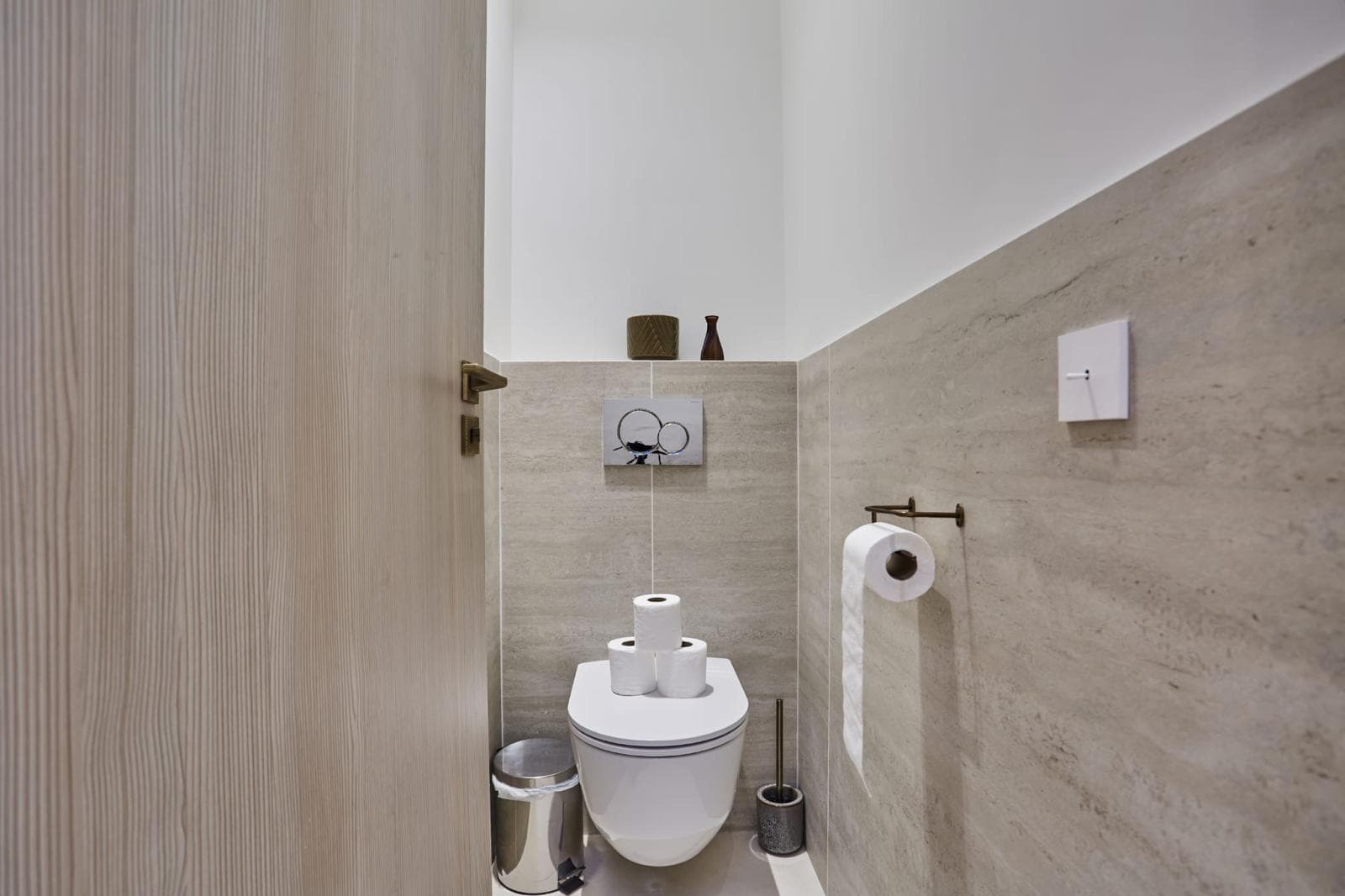 WC suspendu avec plaque de commande encastrée et murs habillés de travertin